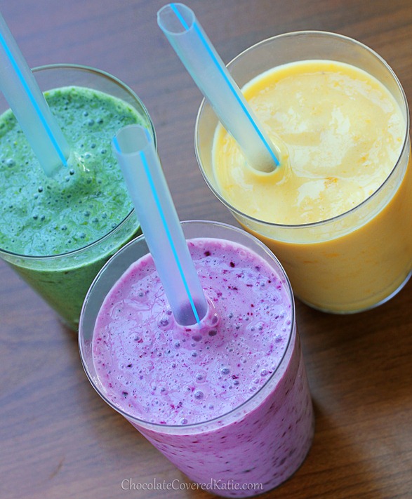 Three brightly coloured smoothies in glasses with clear straws.