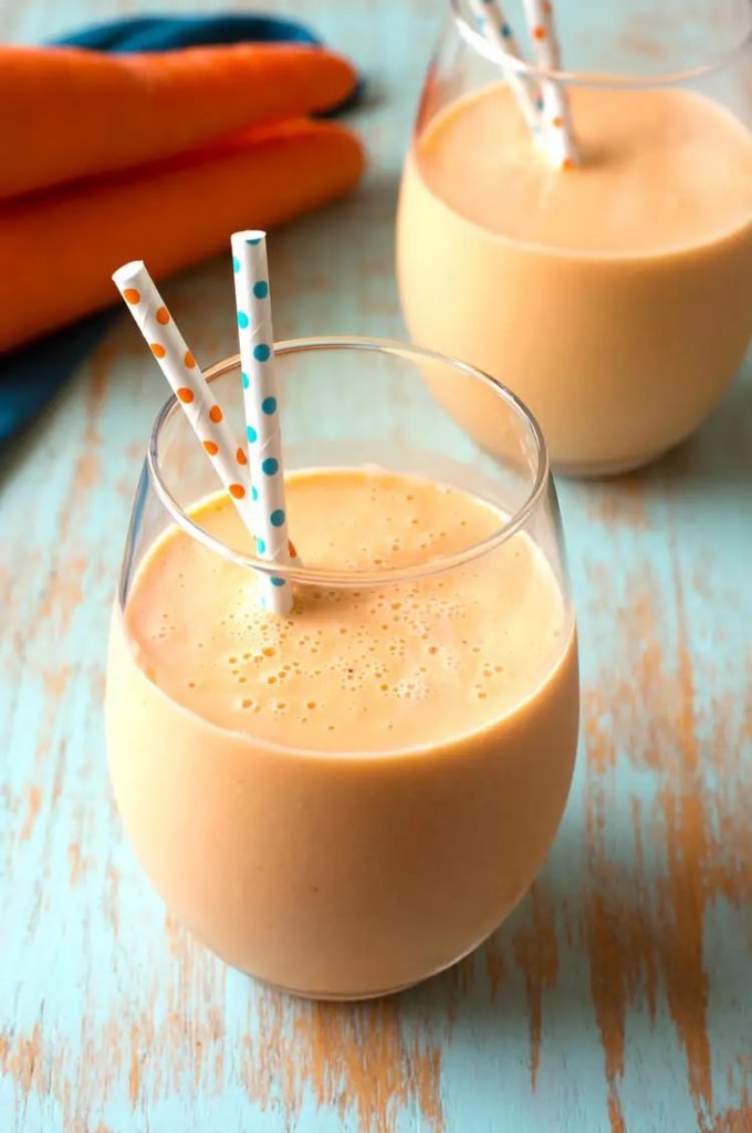 Two glasses of orange smoothies with polka dot straws.
