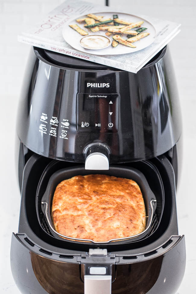Cooked banana bread loaf in an air fryer, with cook book on top