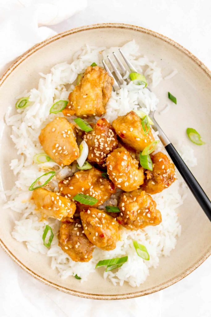 Battered chicken pieces on bed of white rice and spring onions