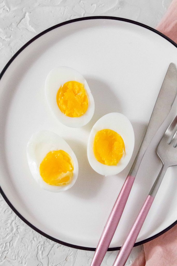 3 egg air fried egg halves on white plate with knife and fork