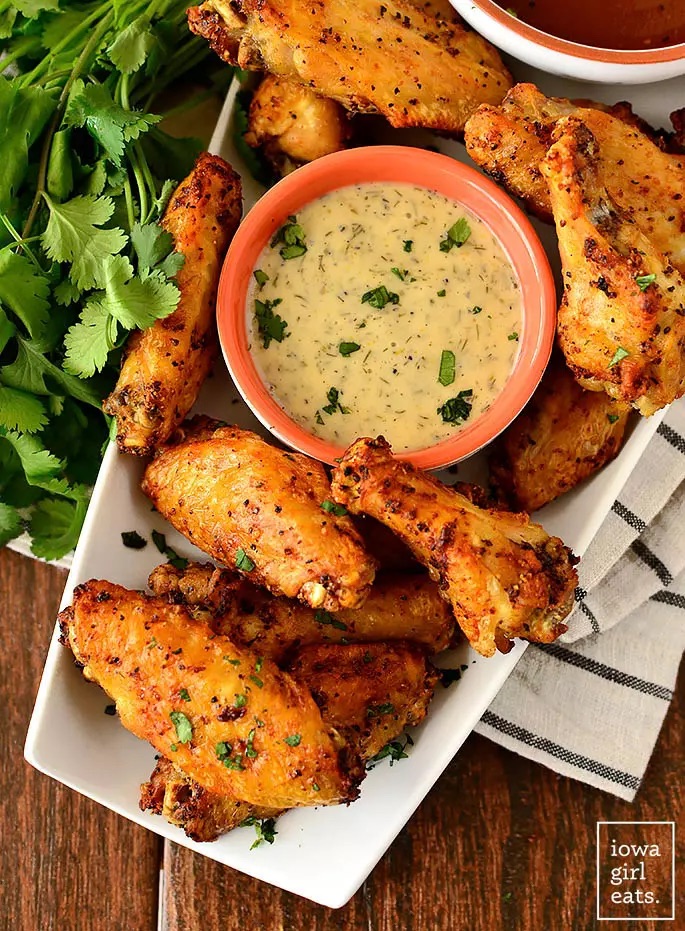 Air fried chicken wings on rectangular plate around bowl of dip