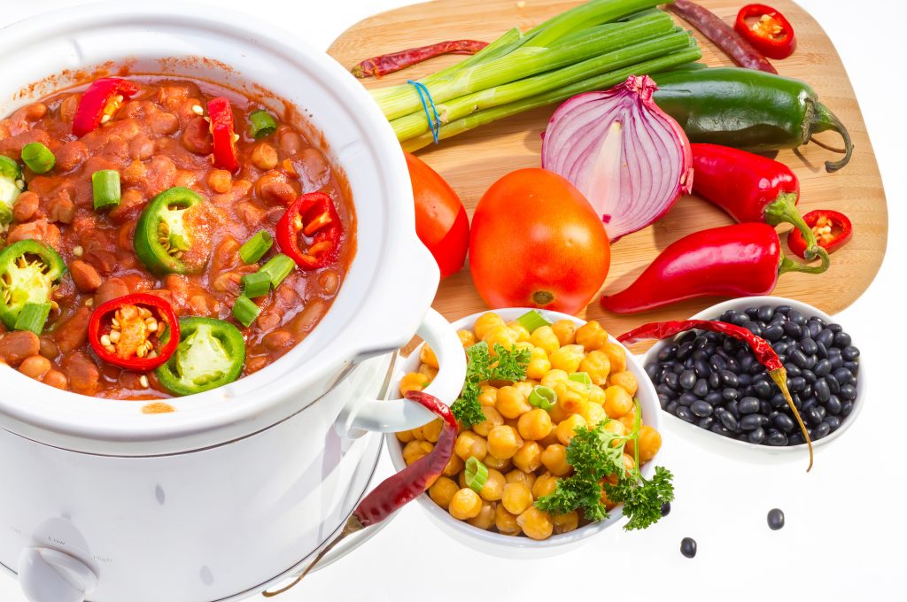 Beans and Chilli peppers cooked in a slow cooker with assorted raw vegetables