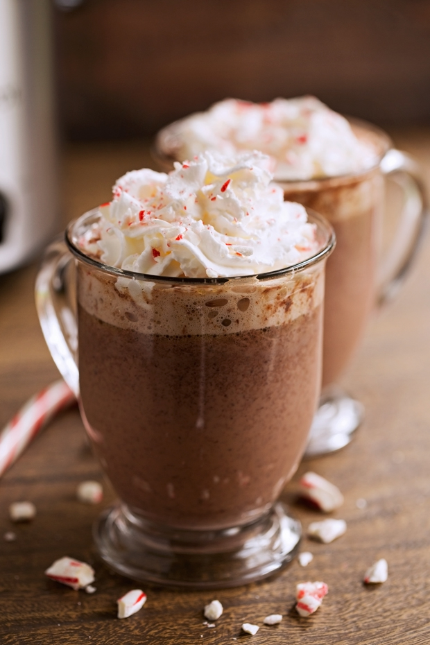 Clear glass mugs of hot chocolate topped with whipped cream