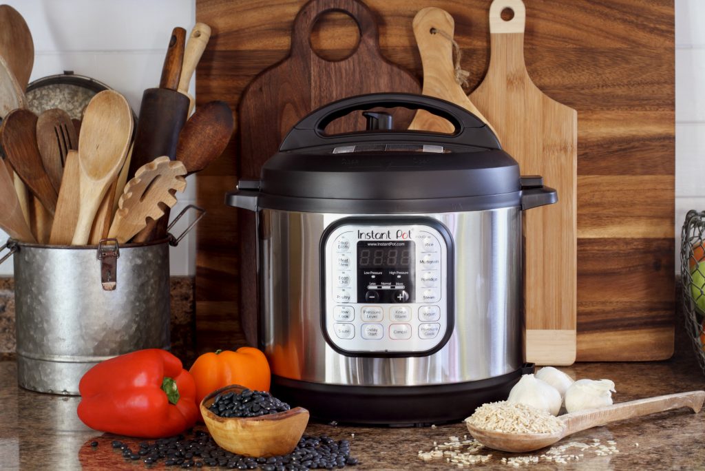 Instant Pot on counter with utensils and chopping boards behind and ingredients in front
