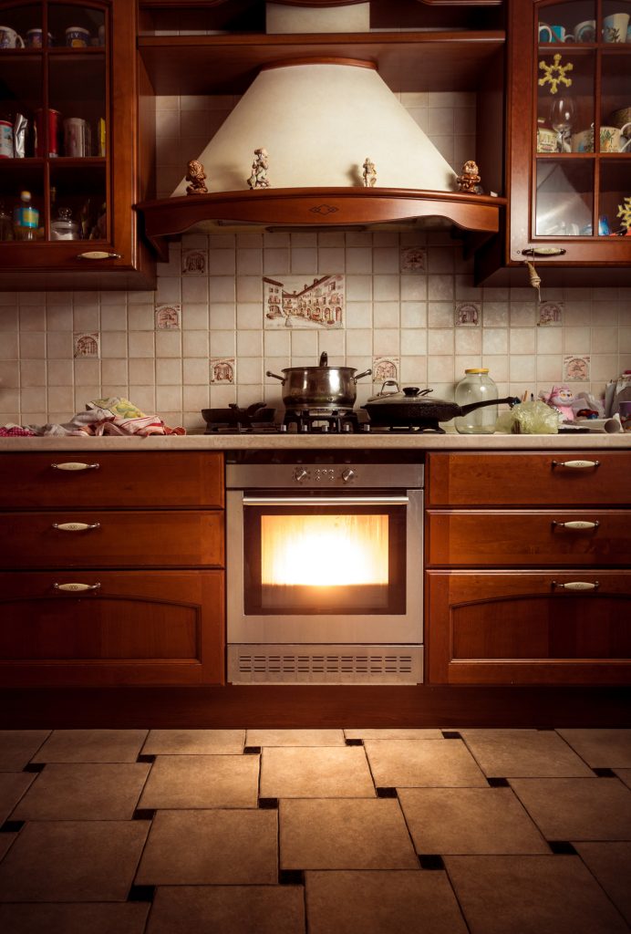 Oven in country style kitchen with bright light coming from it indicating it's very hot.
