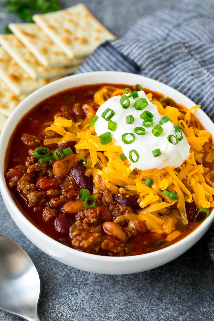 Bowl of chili con carne with cheese, cream and chopped onions on top