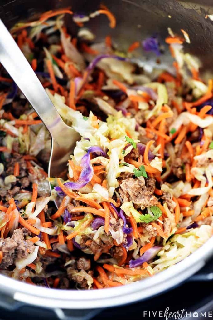 Meat cooked with shredded vegetables being spooned out of large pot