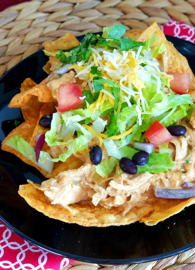Shredded chicken in a creamy sauce on top of taco shells and covered with large green salad