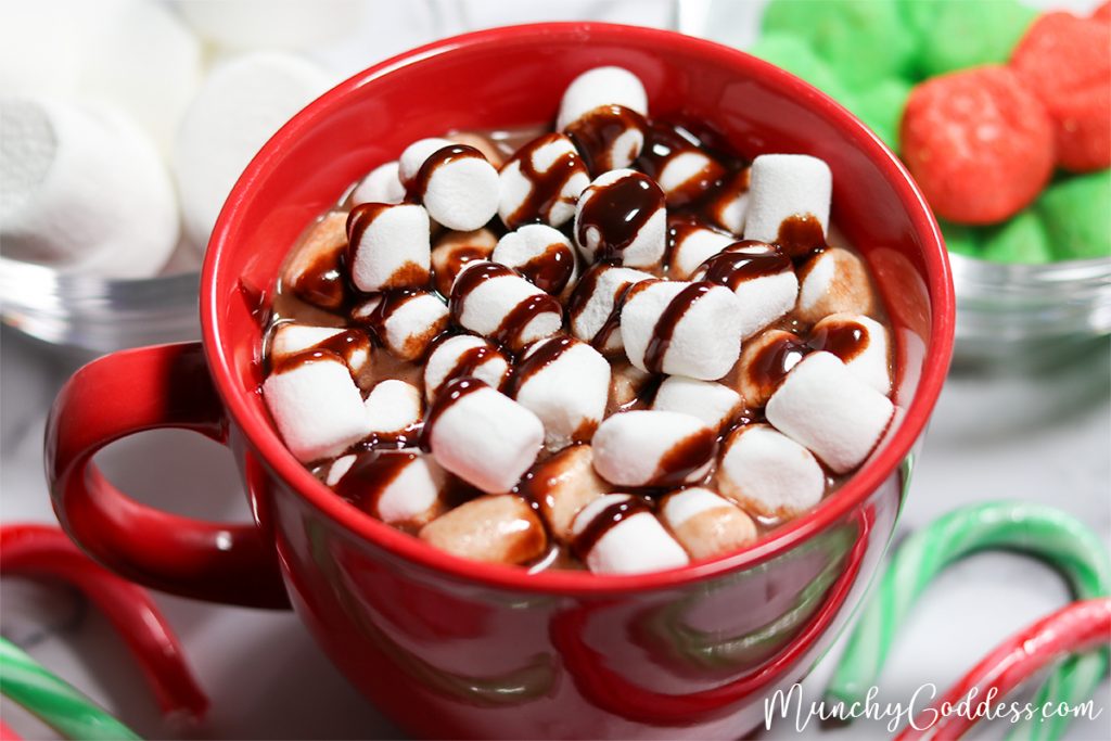 Large red mug of hot chocolate with marshmallows and chocolate sauce on top