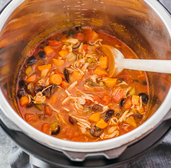 Shredded chicken and vegetables in red tomato sauce in silver cooking pot