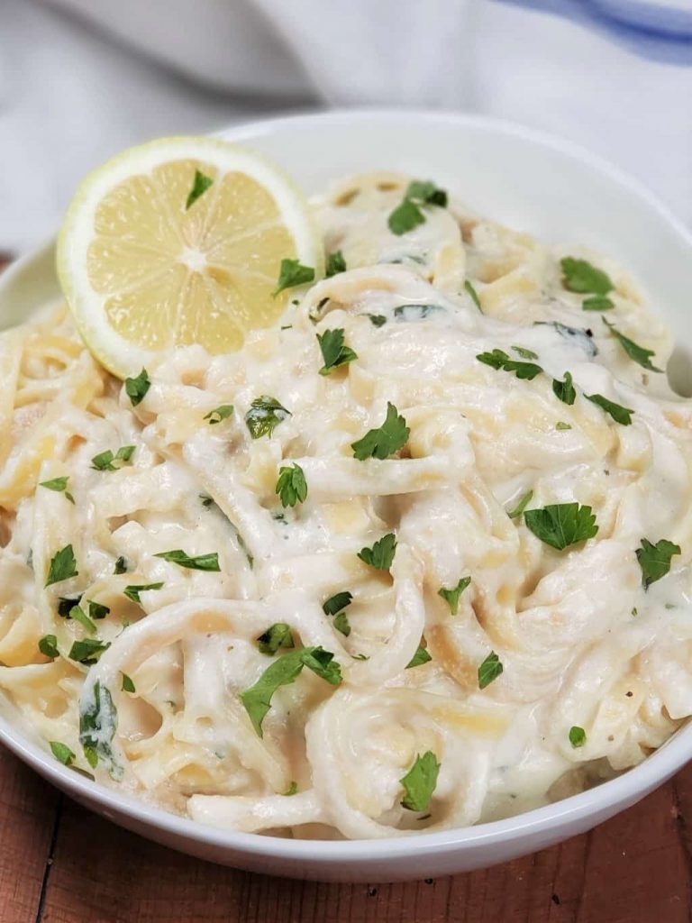 Fettucine pasta coated in white sauce and served with herb and lemon garnish