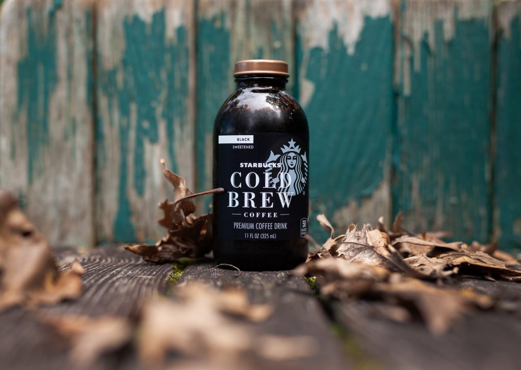 Bottle of Starbucks Cold Brew Coffee on wooden table with leaves