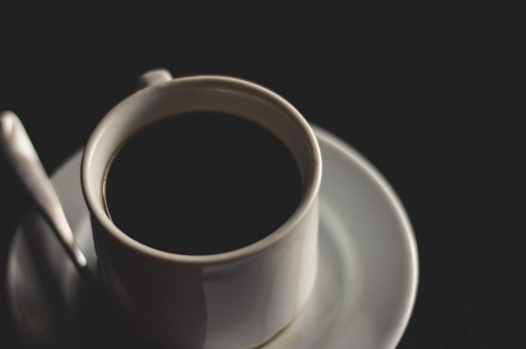 Black coffee in a white cup against a dark background.