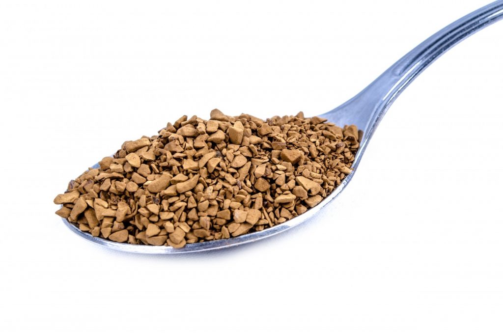 A teaspoon of instant coffee granules on a white background