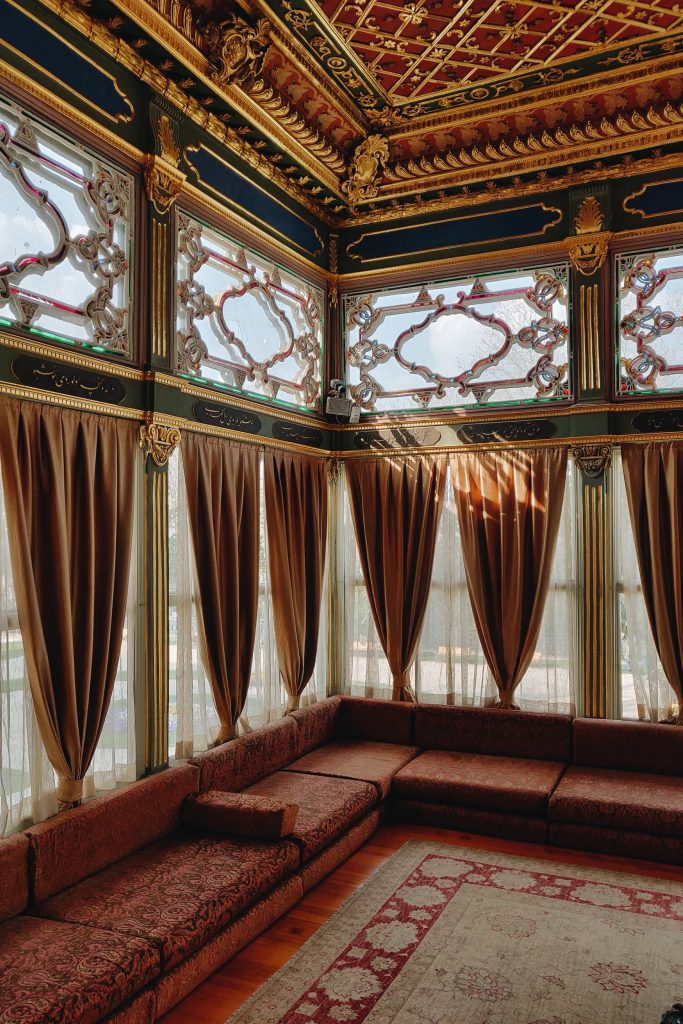 Corner of ornately decorated room with gold decorative ceiling and Turkish rug on floor