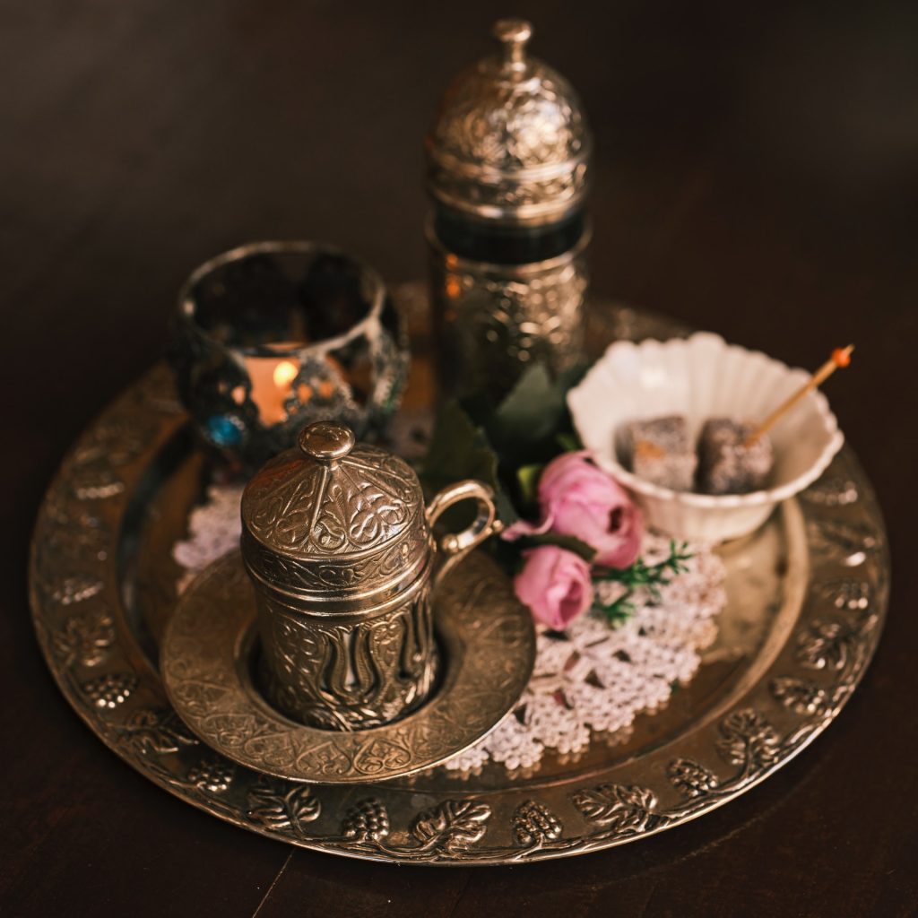 Ornate silver tray with candle and decorated metal cup with lid.