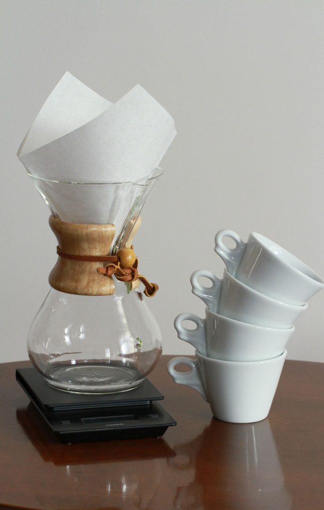 Coffee jug with filter in top and 4 white cups next to it