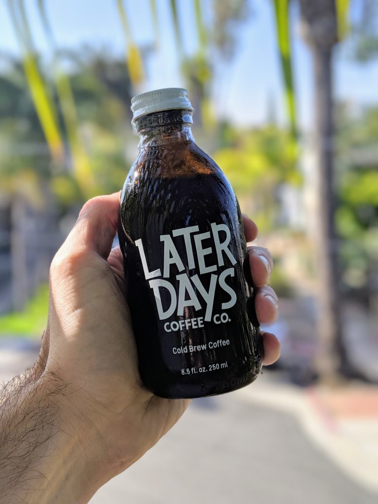 Hand holding bottle of Later Days cold brew coffee with sunny background